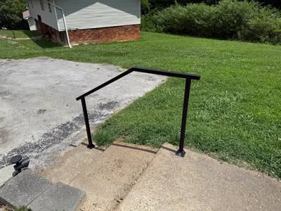 Simple black handrail over concrete garden steps viewed from the top landing