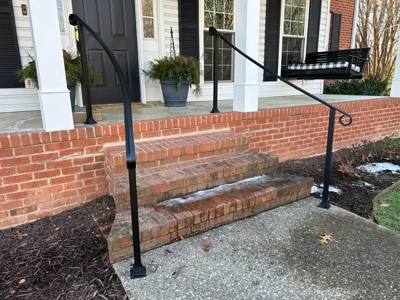 Simple black handrails beside broad brick front steps