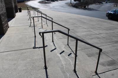Simple black handrails following a wide sloping concrete walkway