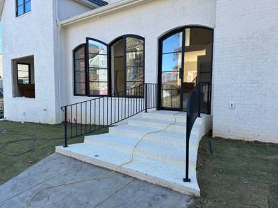 Simple black railings flanking concrete steps at a white building with arched windows