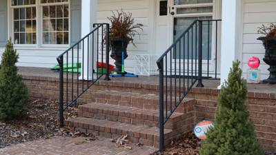 Simple black railings on brick porch steps at a white-sided house