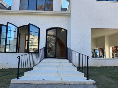 Simple black railings on wide concrete entrance steps below arched windows
