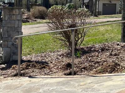 Simple straight handrail bordering a landscaped sloping walkway