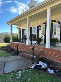 Single black handrail beside a brick porch with white columns