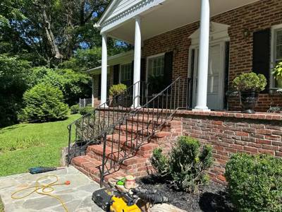 Slender black railings on brick steps leading to a columned porch