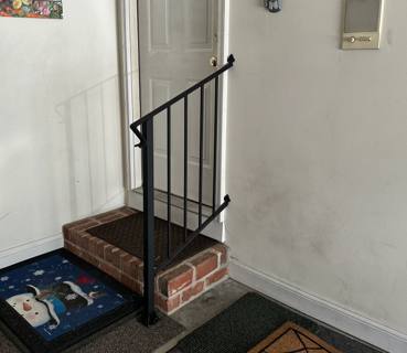 Small black railing beside interior brick steps and a white door