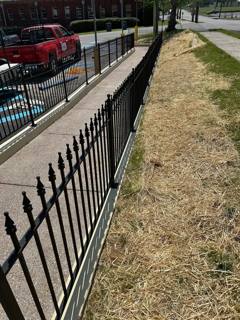 Spear-top black fence alongside a sloping paved walkway