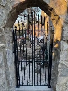 Spear-top black garden gate fitted inside a stone arch