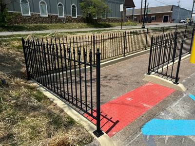 Spear-top fence around a walkway entrance with painted pavement markings