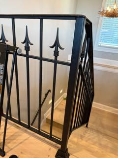Spear-topped black interior stair railing beside pale tile