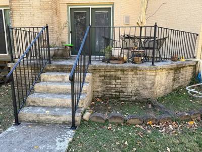 Stone patio with black perimeter railing and paired stair handrails