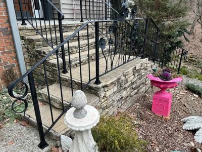 Stone porch stairs with curled handrails and flower-decorated railing panels