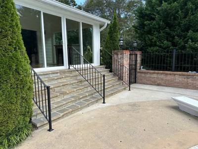 Stone porch steps and landing enclosed by black vertical-bar railings