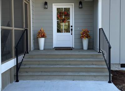 Straight black picket railings flanking gray front porch steps