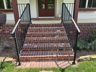 Straight black railings framing wide red-brick porch steps