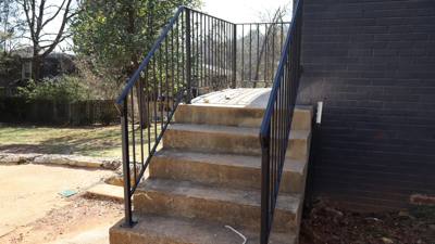 Straight black stair railings viewed from the foot of concrete steps