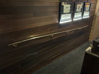 Straight interior handrail mounted to a wood wall beneath display windows