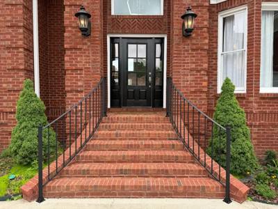 Symmetrical black stair railings at a red brick front entrance