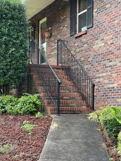Tall black railings following narrow brick steps along a house wall