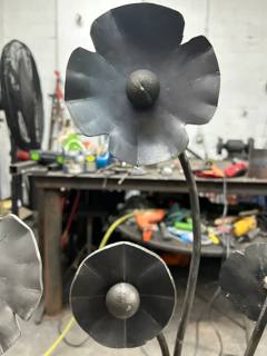 Two sculpted metal flowers on curved stems in a workshop
