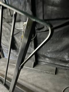 Unfinished curved handrail end beside metal fabrication equipment