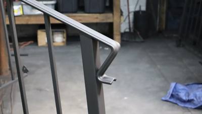 Unfinished handrail return curving around a square post