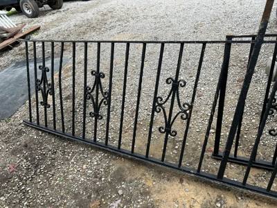 Uninstalled black railing panel with scroll accents on a workshop floor