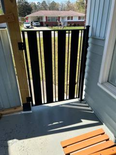 Vertical-picket black gate in a narrow porch doorway