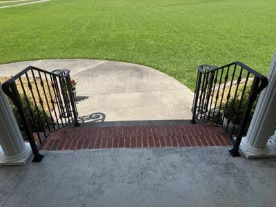 View down curved porch railings toward a circular concrete walk