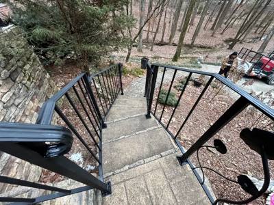 View down stone stairs between vertical-bar railings with curled ends