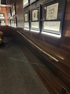 Wall-mounted handrail beneath display windows on a wood-paneled wall