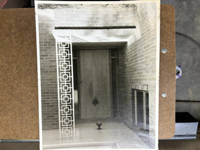 White geometric porch post and railing at a brick entrance