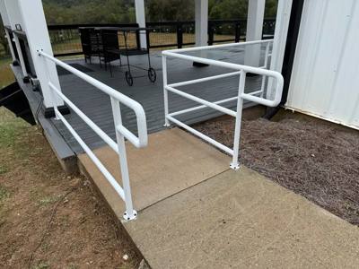 White loop-ended handrails on steps leading to a gray deck