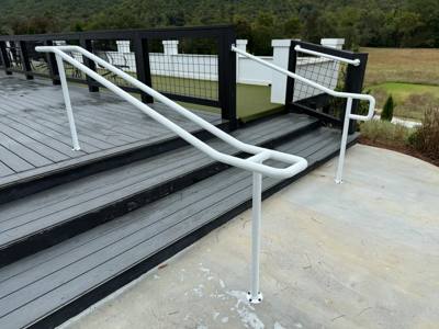 White loop-ended handrails viewed from the foot of gray deck steps