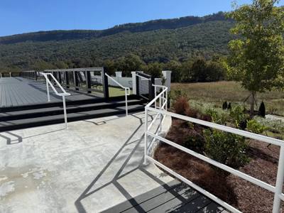 White outdoor handrails bordering concrete steps with a hillside view