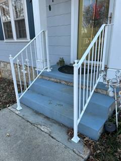 White picket handrails beside short gray entry steps