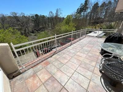 White picket railing enclosing a tiled patio above a wooded slope