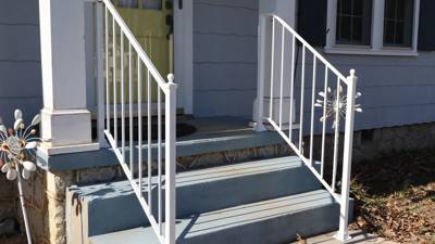 White stair handrails with decorative flower ornaments at a blue porch