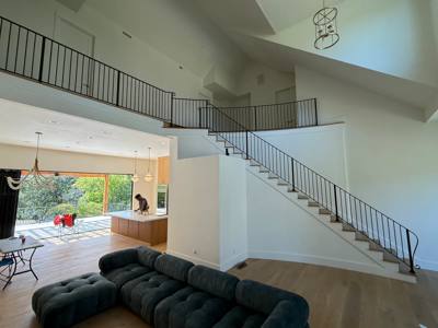 Wide view of wood stairs and upper-level black railings in a bright living area